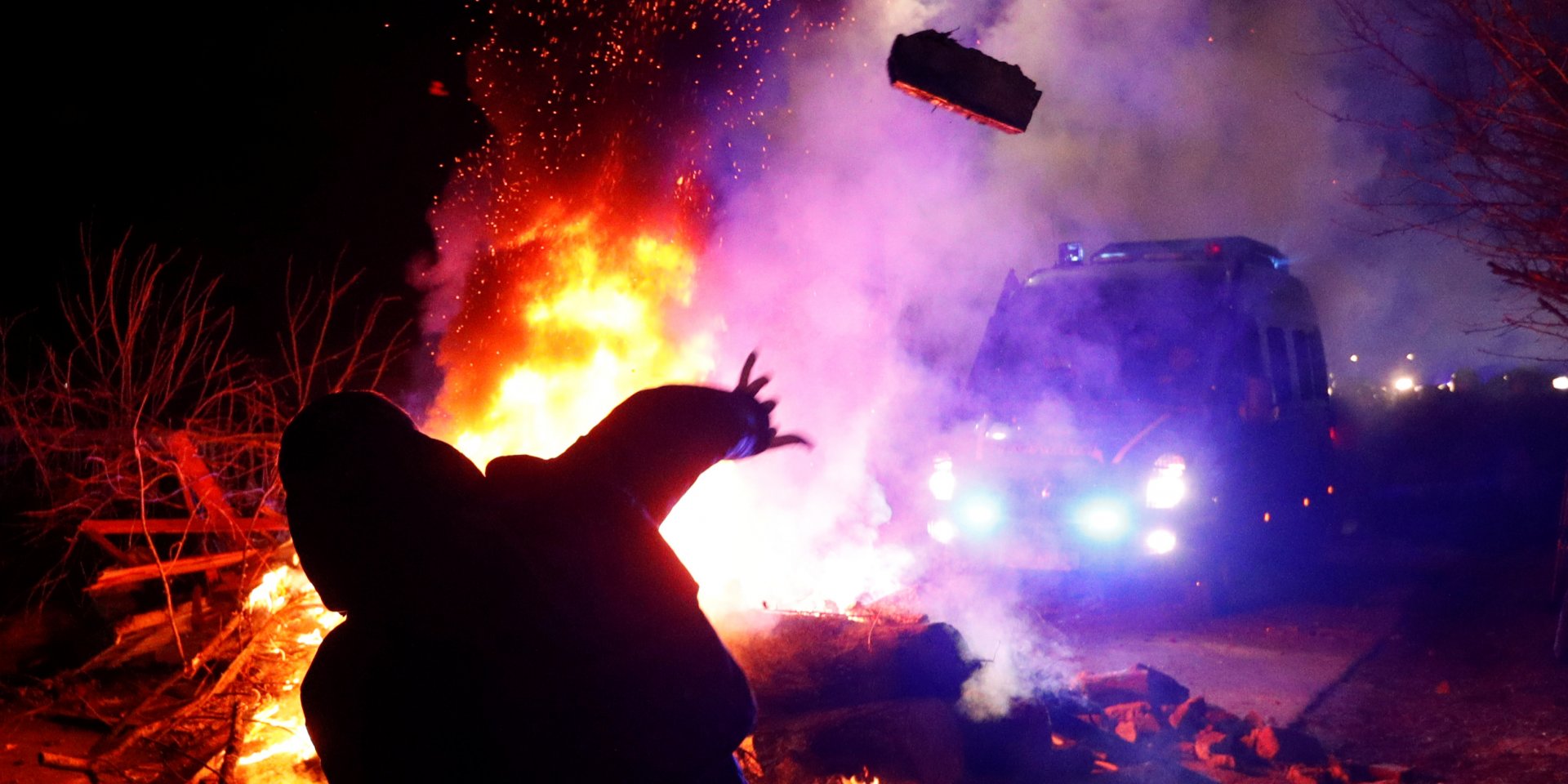 Протестующий бросает кирпич в автобус с эвакуированными (Фото: REUTERS/Valentyn Ogirenko)