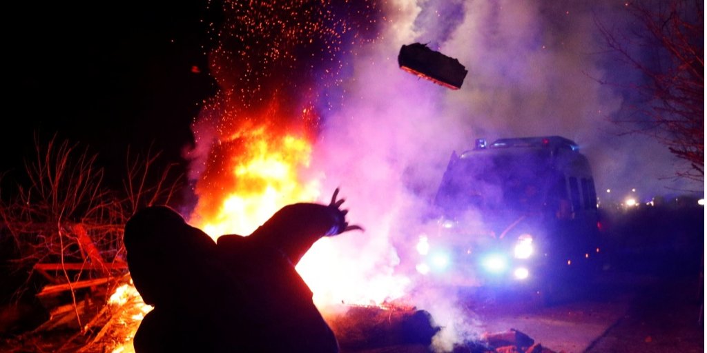 Протестующий бросает кирпич в полицейский автомобиль, сопровождавший автоколонну (Фото: REUTERS/Valentyn Ogirenko)