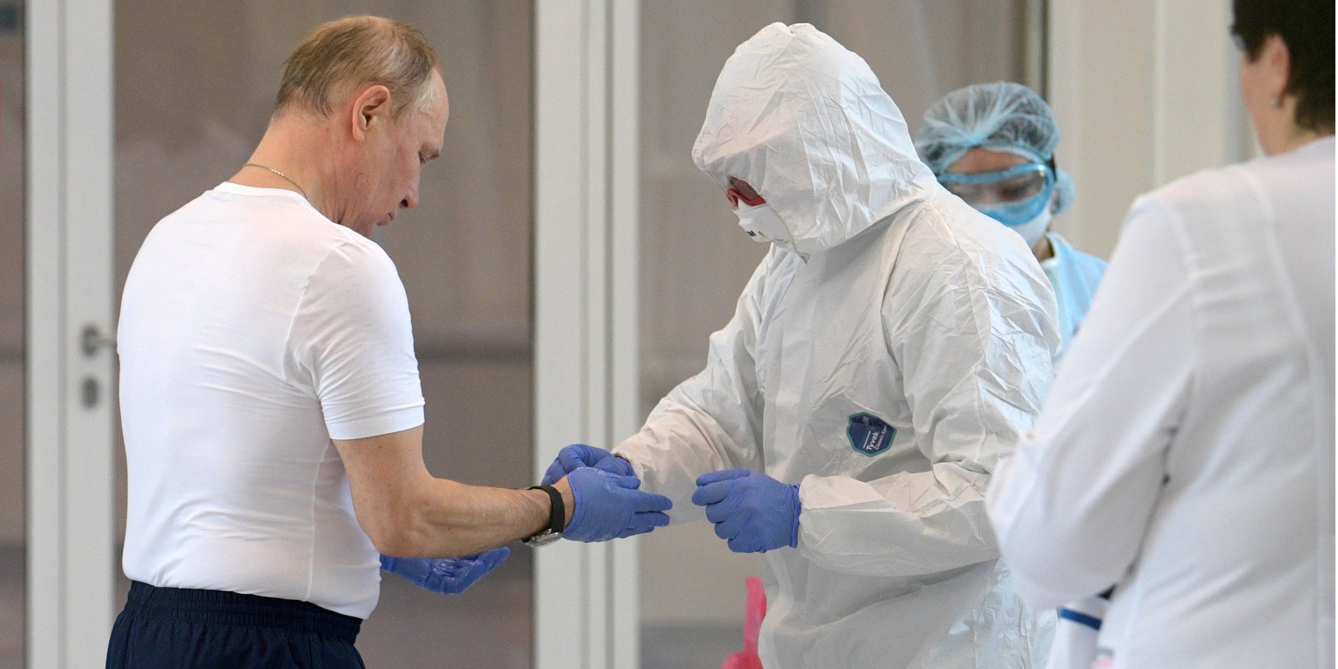 Владимиру Путину помогают снять одноразовые перчатки после визита в больницу, где лечат пациентов с COVID-19 (Фото: Sputnik/Alexey Druzhinin/Kremlin via REUTERS)