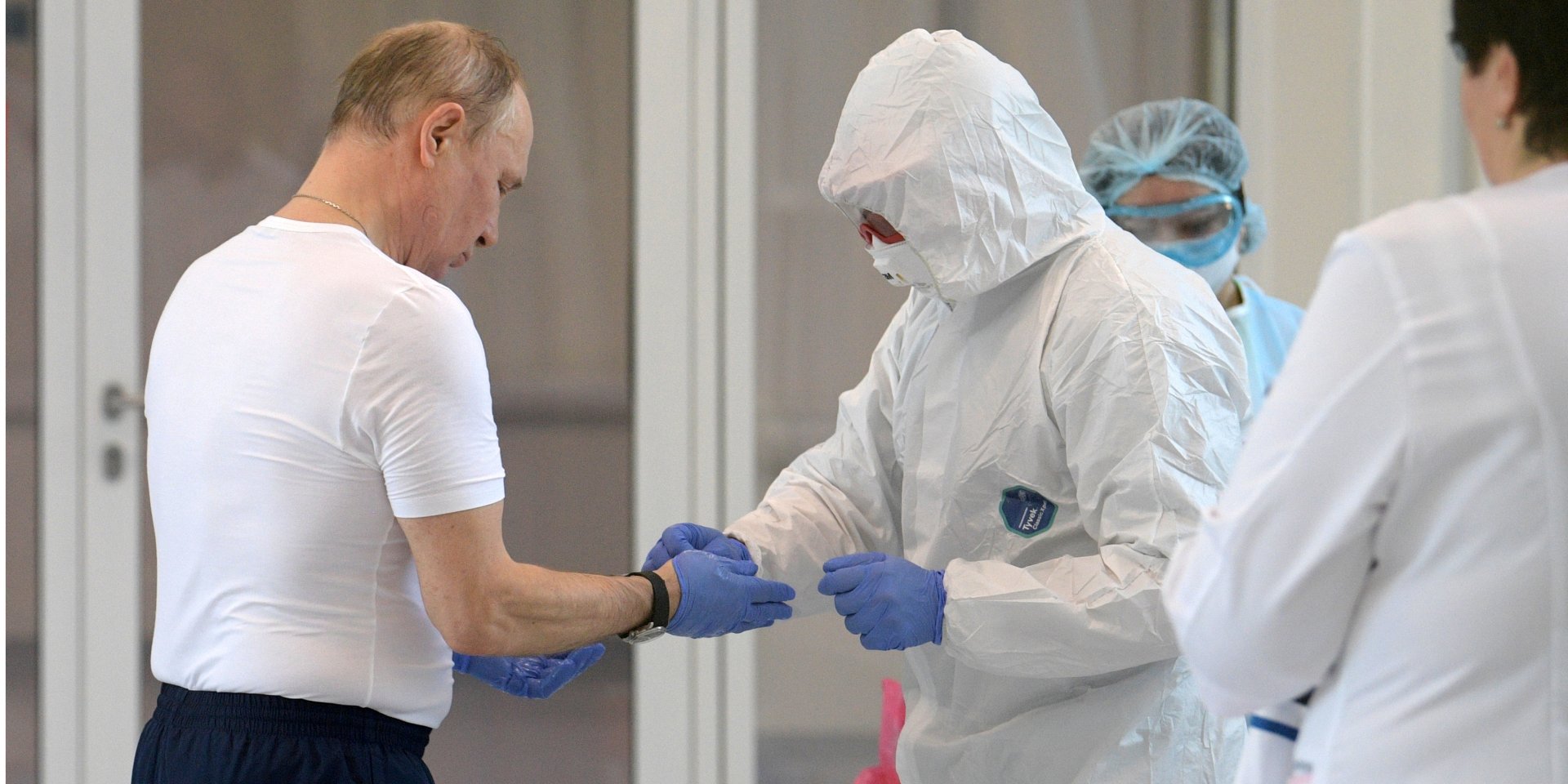 Володимиру Путіну допомагають зняти одноразові рукавички після візиту в лікарню, де лікують пацієнтів з COVID-19 (Фото: Sputnik/Alexey Druzhinin/Kremlin via REUTERS)
