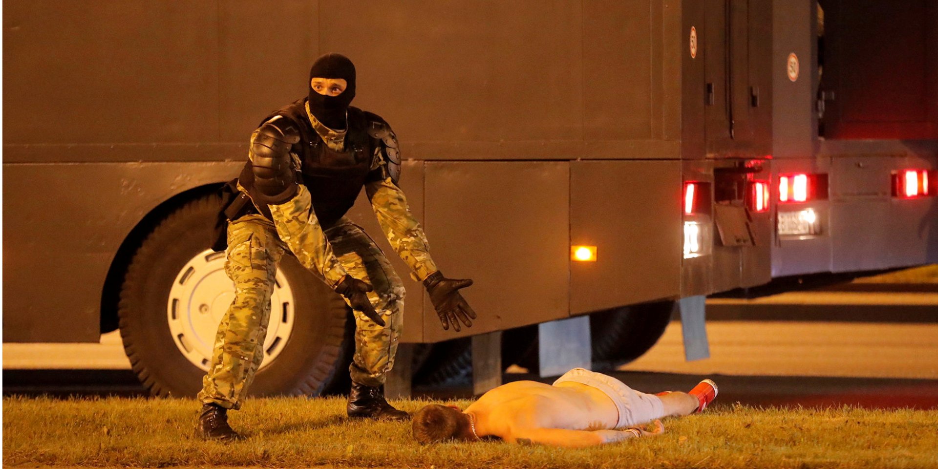 Силовик стоит над раненым Евгением Заичкиным в Минске 9 августа (Фото: REUTERS/Vasily Fedosenko/File photo)