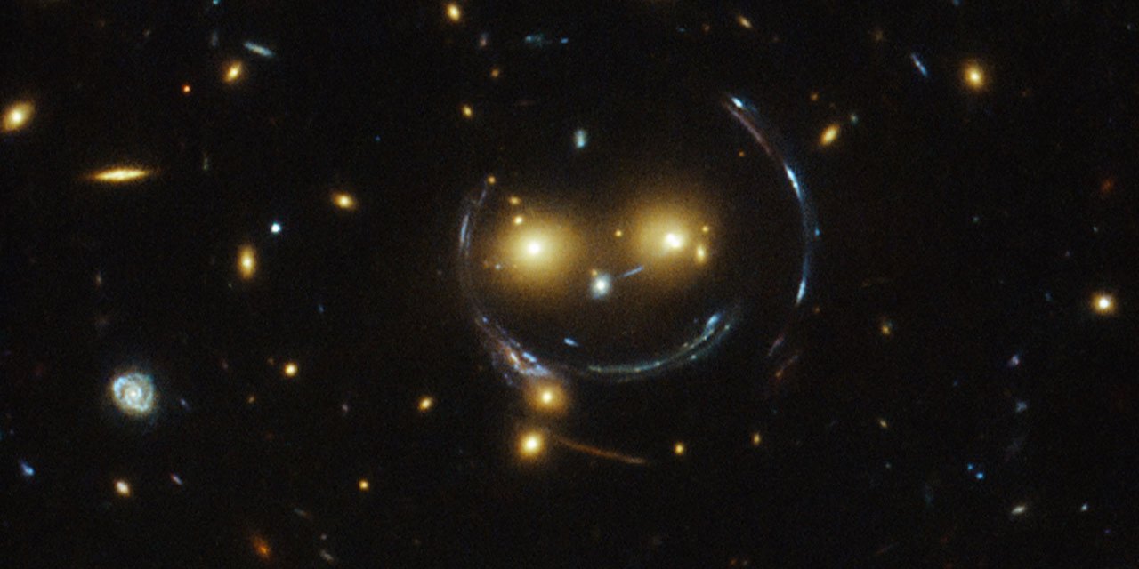 Cкупчення галактик SDSS J1038 + 4849 «посміхається» через ефект гравітаційного лінзування, яке запропонували використовувати дослідники (Фото: NASA/ESA)