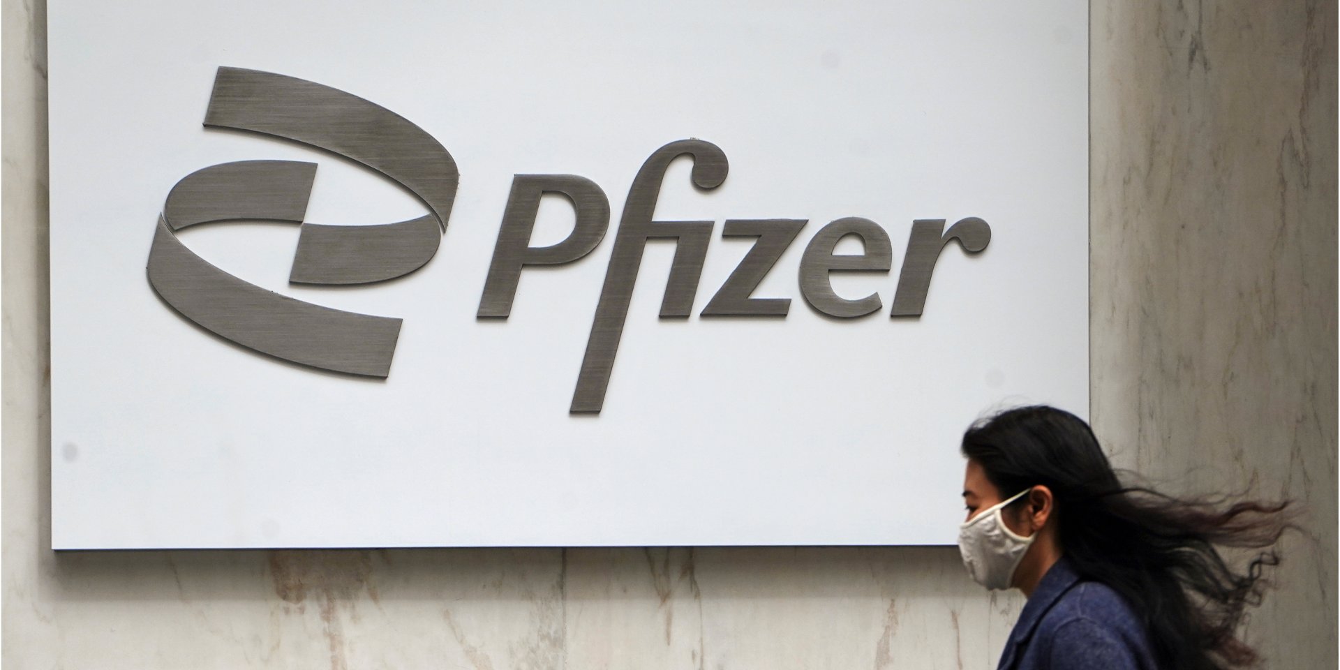 Жінка на тлі логотипу компанії Pfizer (Фото: REUTERS/Carlo Allegri)