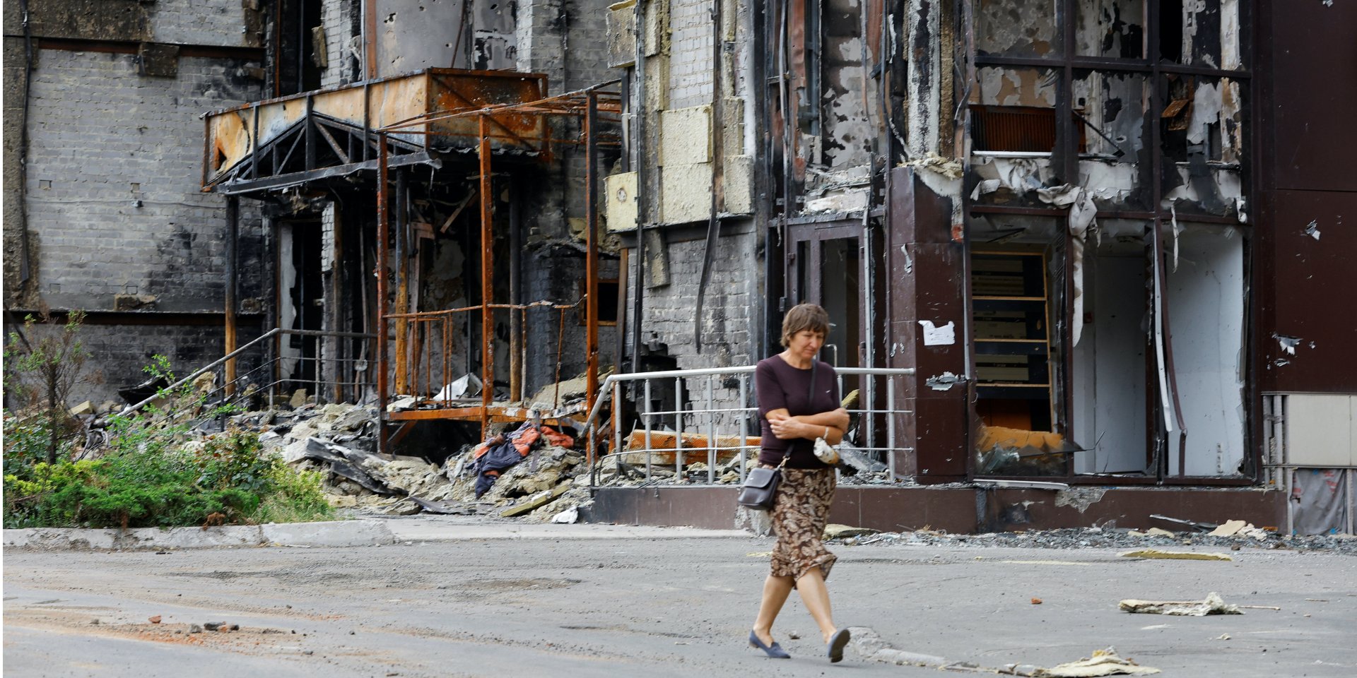 Женщина идет возле разрушенного дома в Мариуполе (Фото: REUTERS/Alexander Ermochenko)