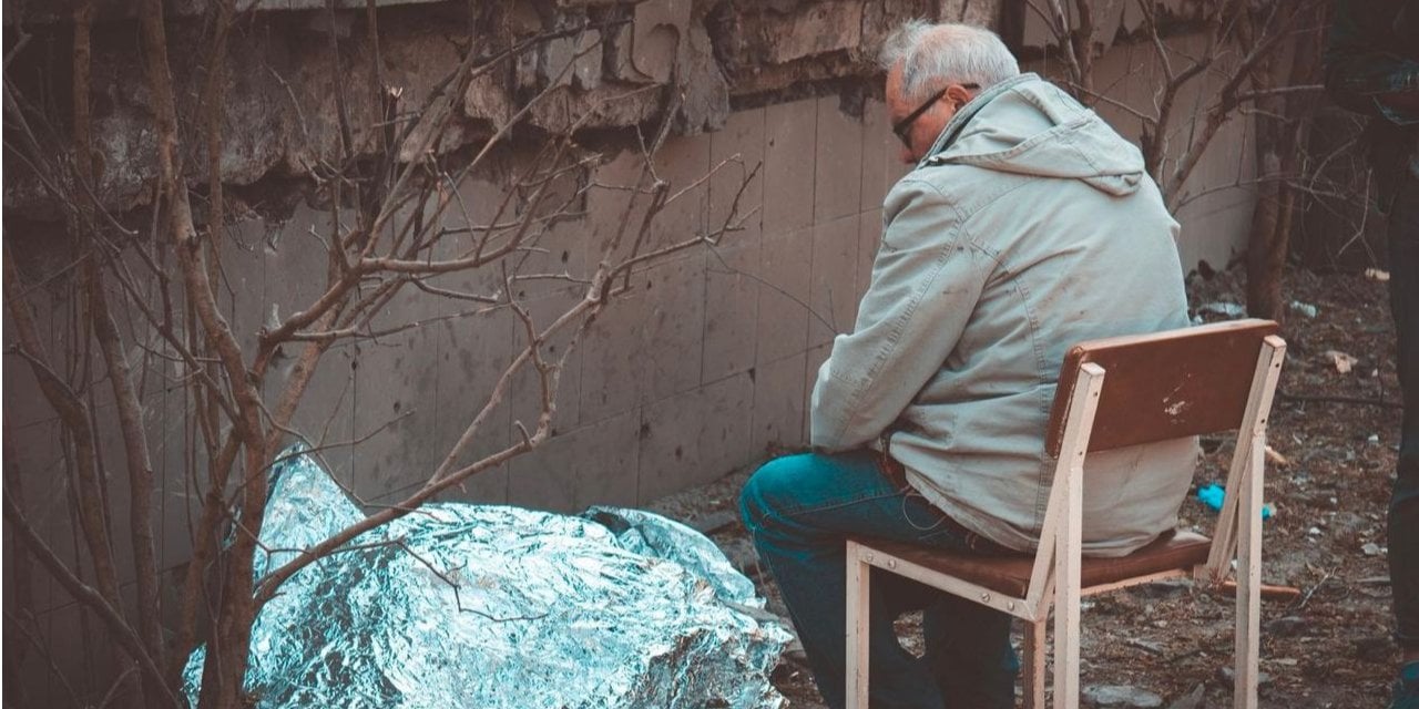 A grandfather sits next to the body of a nine-year-old granddaughter killed in a Russian attack in Kyiv (Photo: Serhii Okunev)