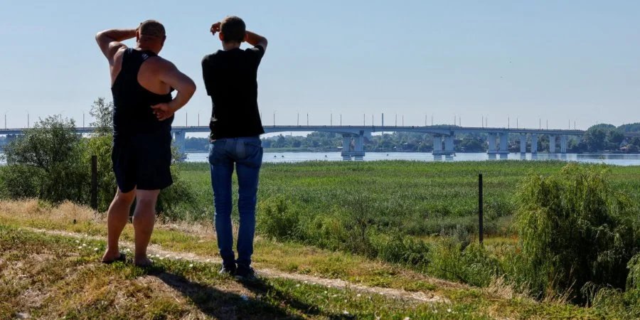 Two men look at the Antonivskyi Bridge in Kherson, which has not yet been destroyed, July 27, 2022 (Photo: Alexander Ermochenko/REUTERS)
