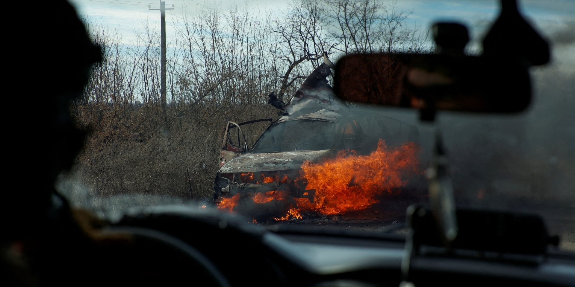 Ukrainian soldiers drive past a burning car (Photo: Radio Free Europe/Radio Liberty/Serhii Nuzhnenko via REUTERS)