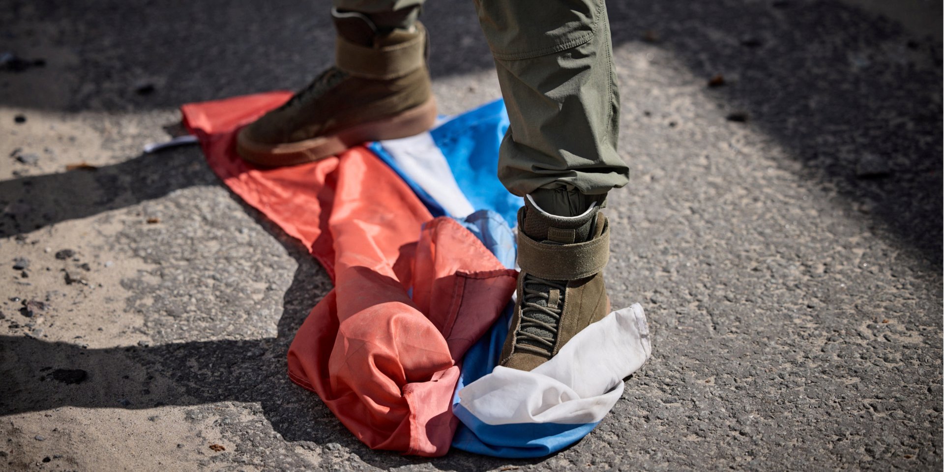 A man tramples on the Russian flag in the de-occupied territory of Kharkiv Oblast (Photo: Ukrainian Presidential Press Service/Handout via REUTERS)