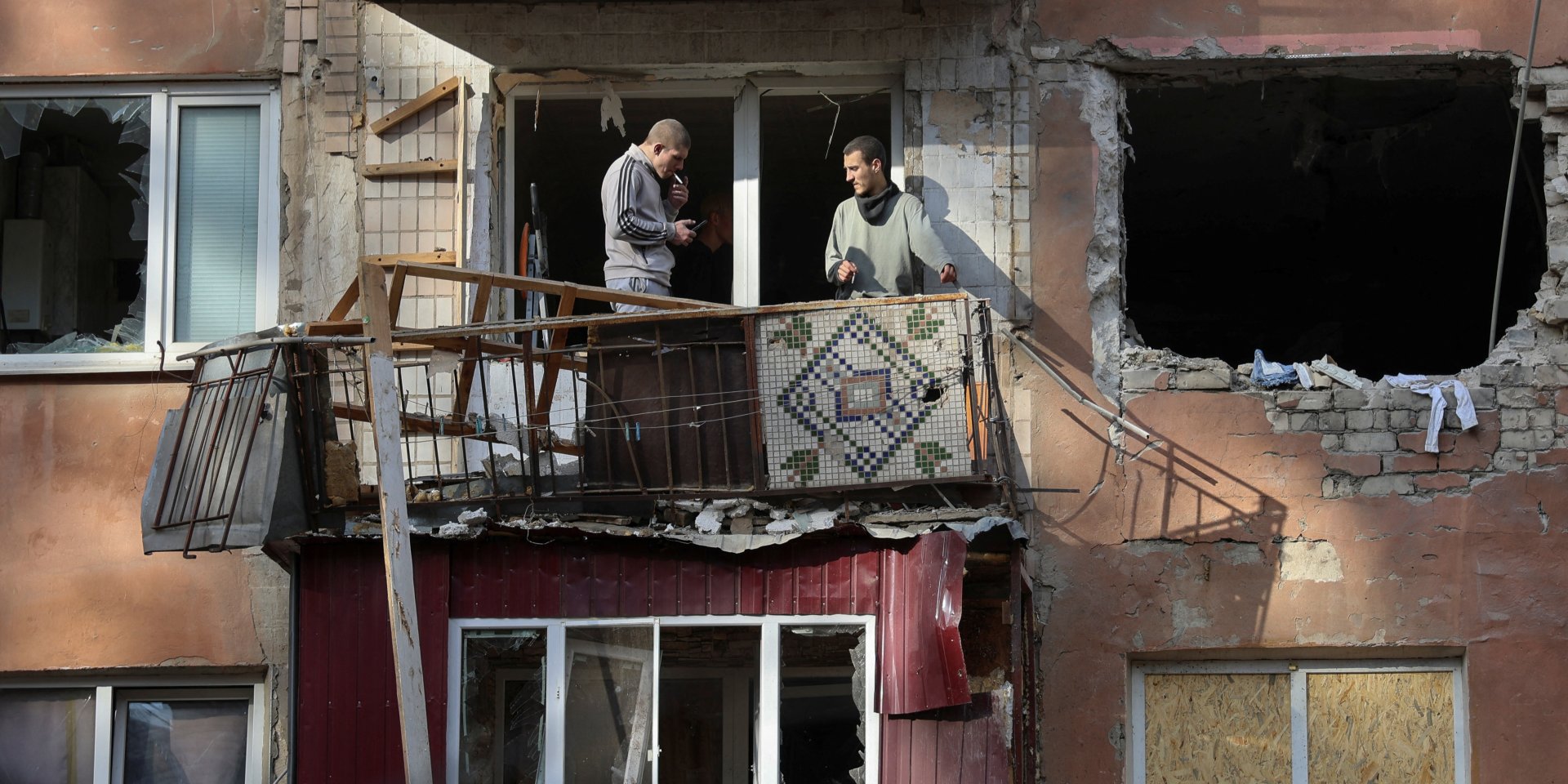 Мужчины курят на балконе после российской атаки по городу Херсон, 8 ноября 2024 года (Фото: REUTERS/Ivan Antypenko)