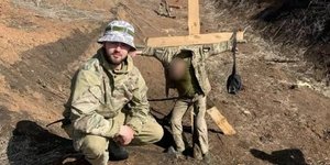 Владислав Пастух фотографується на тлі прив’язаного до хреста українського військового (Фото: УП)