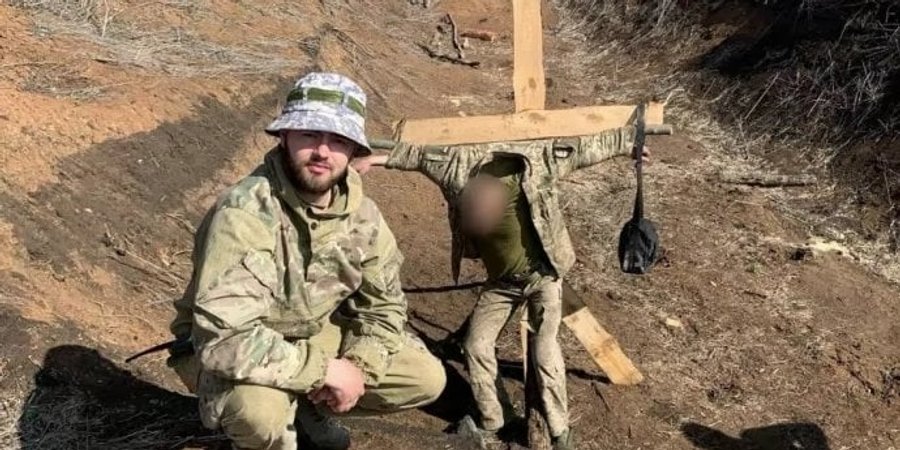 Владислав Пастух на тлі прив’язаного до хреста українського військового (Фото: Українська правда)