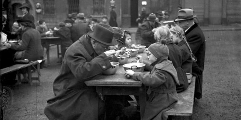 Благодійний обід з «одного казана» у Вормсі, 1938−1939 роки. Традицію запровадив Адольф Гітлер: першої неділі місяця на сімейні обіди подавали замість звичайної смаженої свинини з картоплею овочеве рагу або макарони чи бобове п’юре, іноді притрушені подрібленим м’ясом. Це мало сприяти скромності та ощадності у німців, а ще давало відчуття рівності між багатими та бідними (Фото: Bundesarchiv)