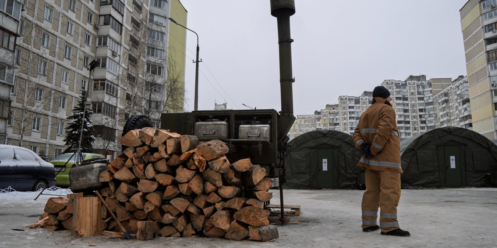Сотрудник ГСЧС стоит на фоне развернутого палаточного городка на столичной Троещине (Фото: Сергей Окунев, NV)