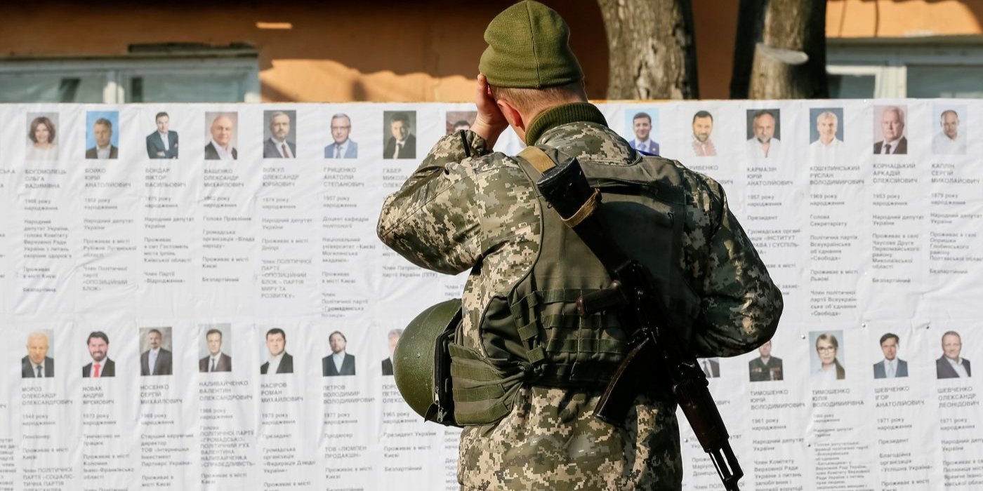 Украинский военнослужащий читает информацию о кандидатах в президенты на избирательном участке вблизи линии фронта, во время президентских выборов в селе Зайцево, 31 марта 2019 год (Фото: REUTERS/Gleb Garanich)