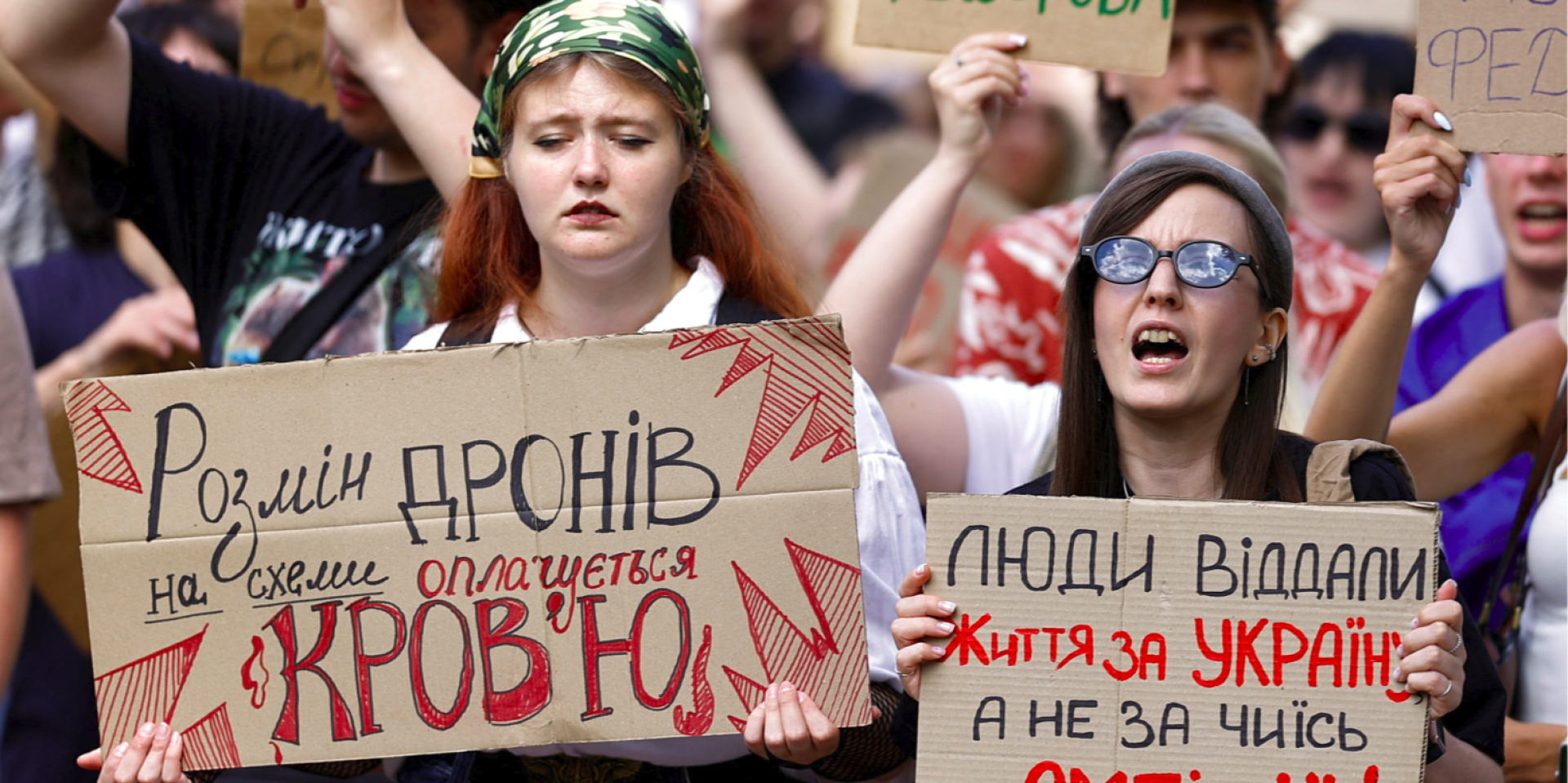 A participant in a protest against Mykhailo Fedorov’s dismissal as defense minister holds a sign reading, “Trading drones for schemes is paid for in blood,” July 17, 2026. (Photo: REUTERS/Valentyn Ogirenko)