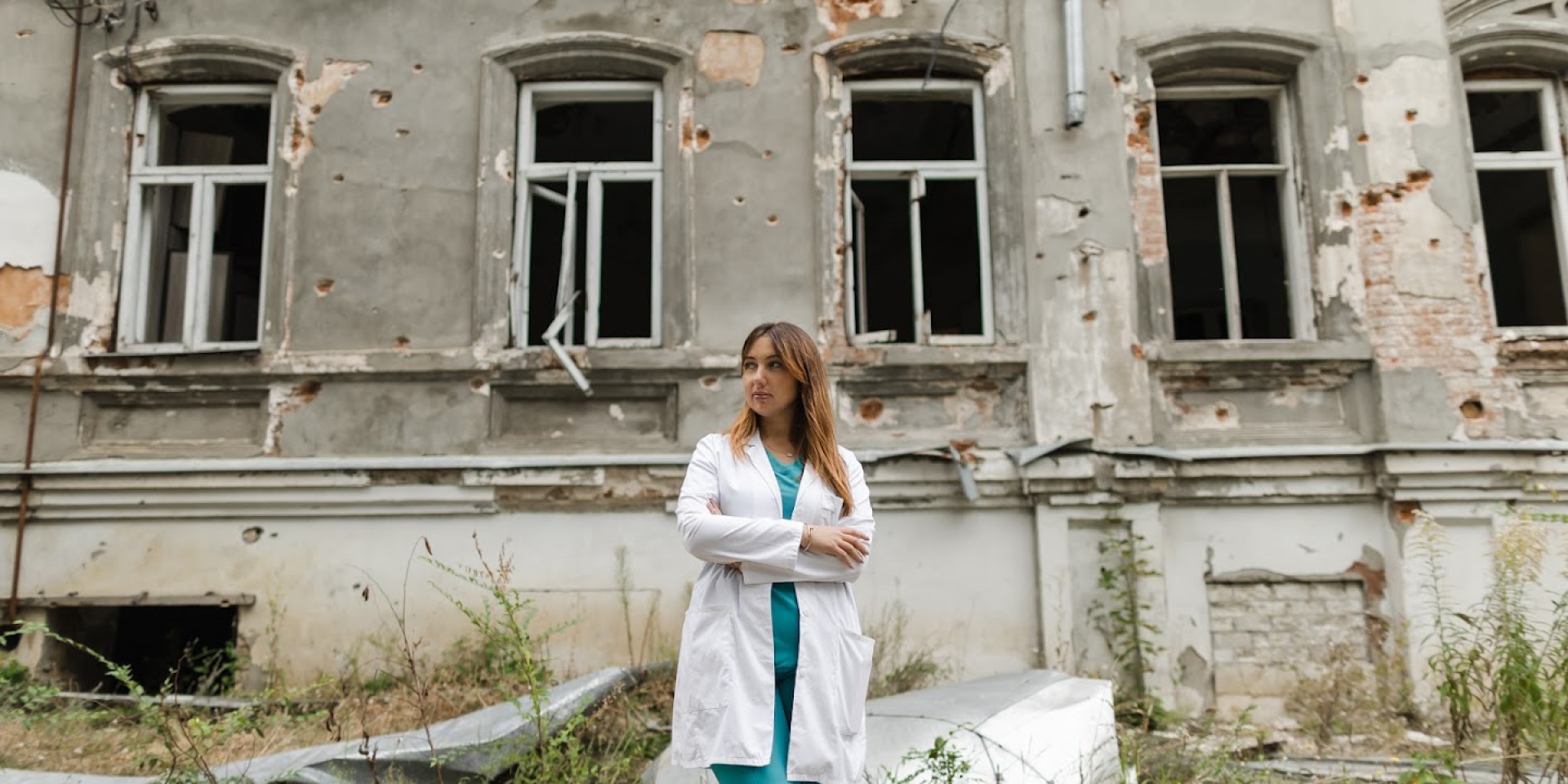 Daria Kantemyr, a family physician, cardiologist and director of the local primary healthcare center, stands in front of a damaged building in Mala Danylivka, Kharkiv Oblast. (Photo: Yuliia Filipchenko)