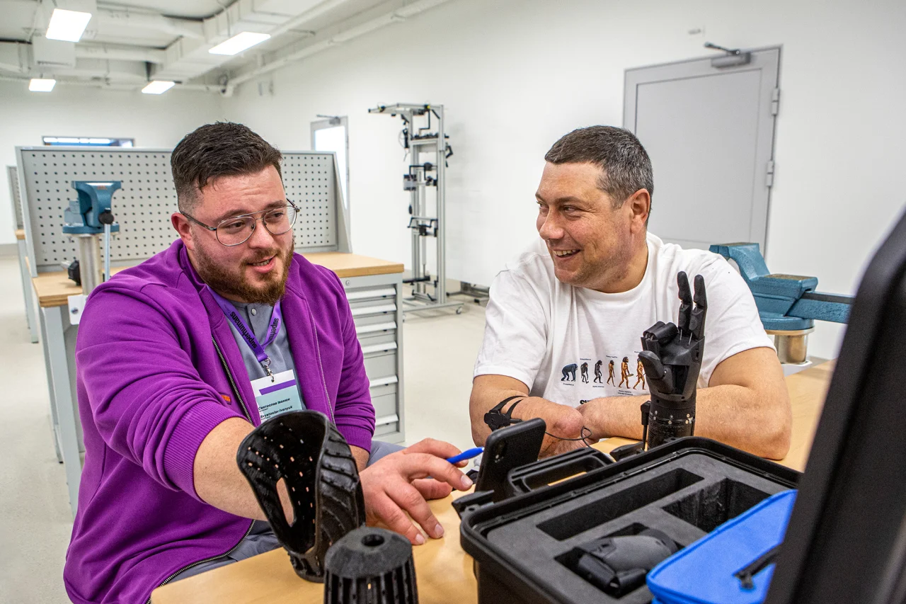 Так происходит управление миоэлектрическим (бионическим) протезом: пациент сокращает мышцу, этот импульс передается к специальным сенсорам, от которых сигнал поступает в «бионическую руку», объясняет протезист Святослав Иванюк (слева). (Фото: Наталья Кравчук / NV)