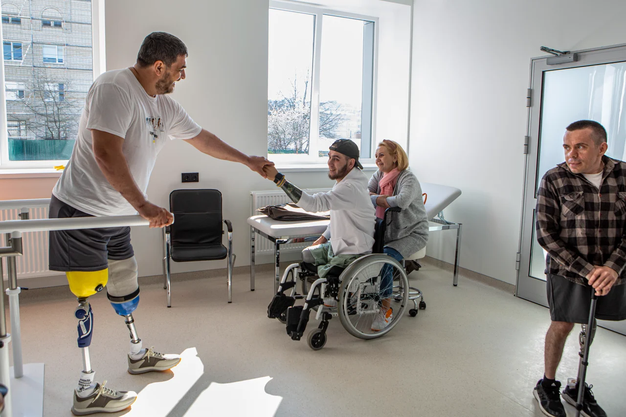 Superhumans Center открыл первую очередь, которая включает в себя лабораторию протезирования и реабилитационный центр. На фото — его пациенты: военные Петр Буряк (на протезах) и Денис Кривенко (на коляске) с мамой Еленой, справа – Валентин Водолажский, гражданский (Фото: Наталья Кравчук / NV)