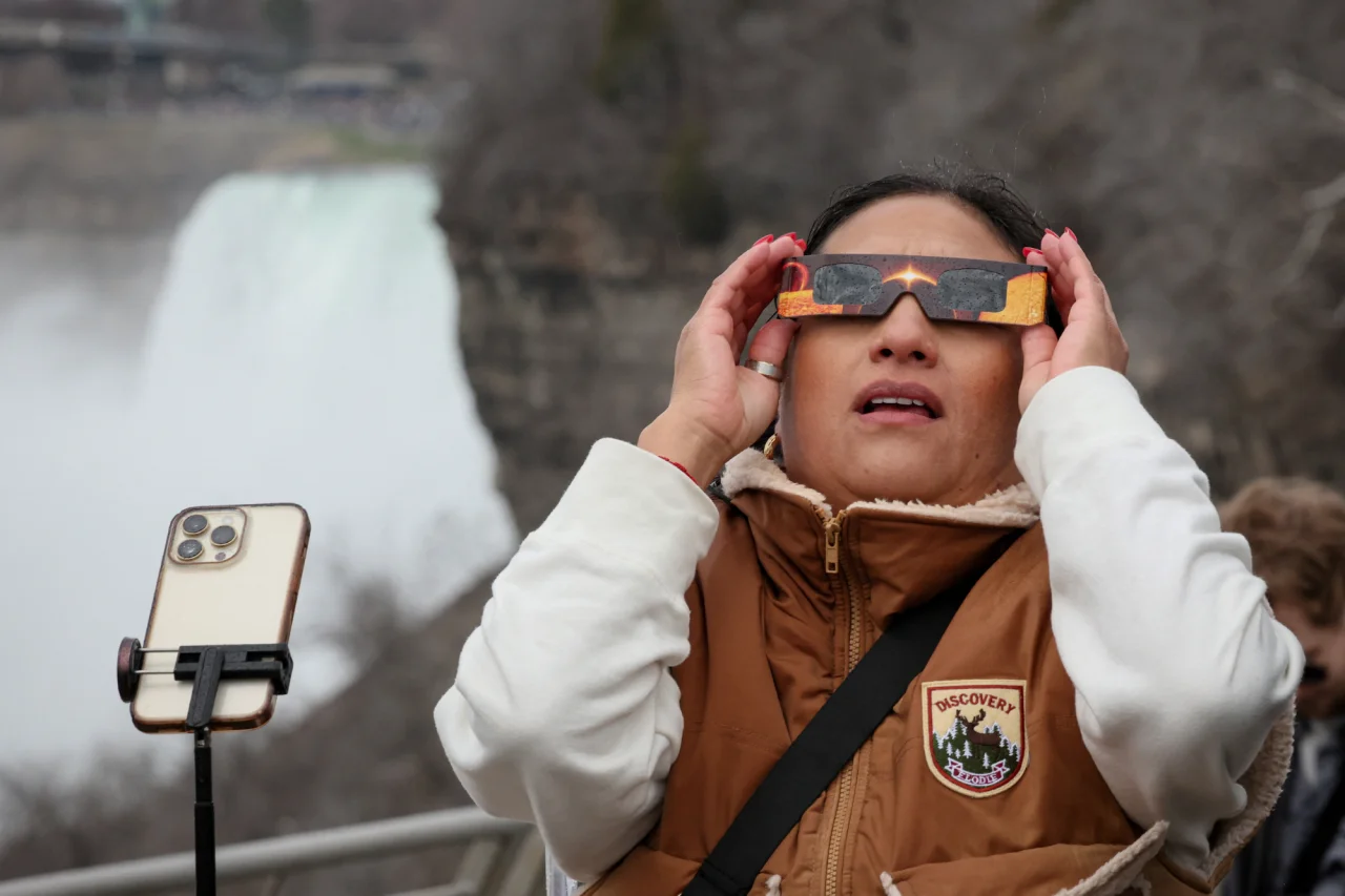 Женщина наблюдает за полным солнечным затмением у Ниагарского водопада, США. (Фото: REUTERS/Brendan McDermid)