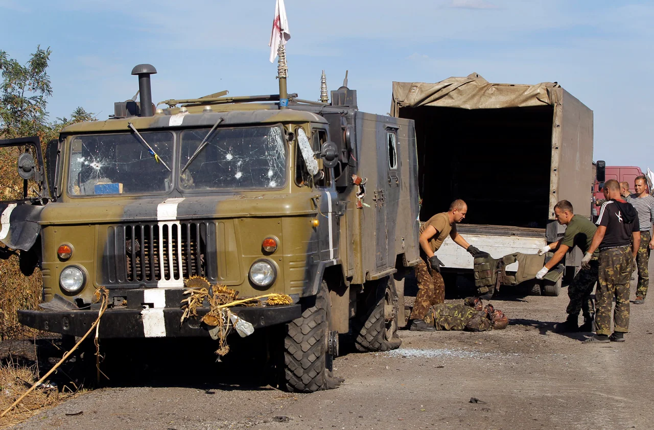 Украинские военнослужащие снимают бронежилет с тела украинского солдата, убитого танковым огнем на востоке Украины 30 августа 2014 года (Фото: AP / Sergei Grits)