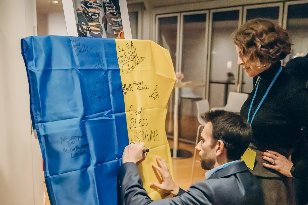 INTEGRITES. Гості Ukrainian Get Together, який INTEGRITES провела в Парижі в 2023 році під час щорічної конференції Міжнародної асоціації юристів (ІВА), пишуть повідомлення бійцям 59 окремої мотопіхотної бригади імені Якова Гандзюка на прапорі України